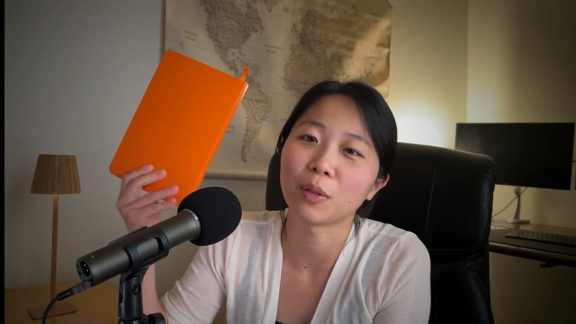 Sandy holding up the orange notebook where she hand-wrote her Ikigai answers before bringing AI into the process